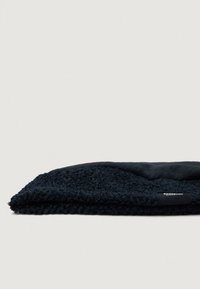Căciulă din tricot negru, cu o suprafață texturată și o secțiune superioară netedă. Prezintă un mic eticheta cu logo pe lateral. Design moale și strâns.