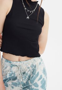 Mustat ribbipinnoitteiset crop-topit, joissa on röyhelökaulus, yhdistettyinä vaaleansinisiin solmittaviin collegehousuihin, joissa on joustava vyötärö.