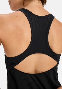 Svart atletisk linne med racerback-design, som har ett texturerat tyg och en utdragningsdetalj bak för ökad andningsförmåga.