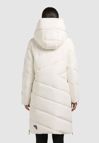 Palton alb lung, matlasat, cu glugă mare. Prezintă un design matlasat diagonal, textură netedă și fermoare la tivul lateral. Logo pe partea stângă jos.