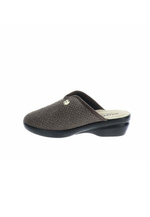 Zapatilla marrón texturizada sin cordones con un pequeño emblema dorado en la parte superior y una suela negra ligeramente elevada.