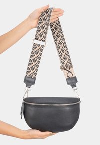 Schwarze Leder-Runde-Handtasche mit strukturierten Oberfläche, silbernem Reißverschluss und einem gemusterten beige-schwarzen Tragegurt mit Metallbeschlägen.