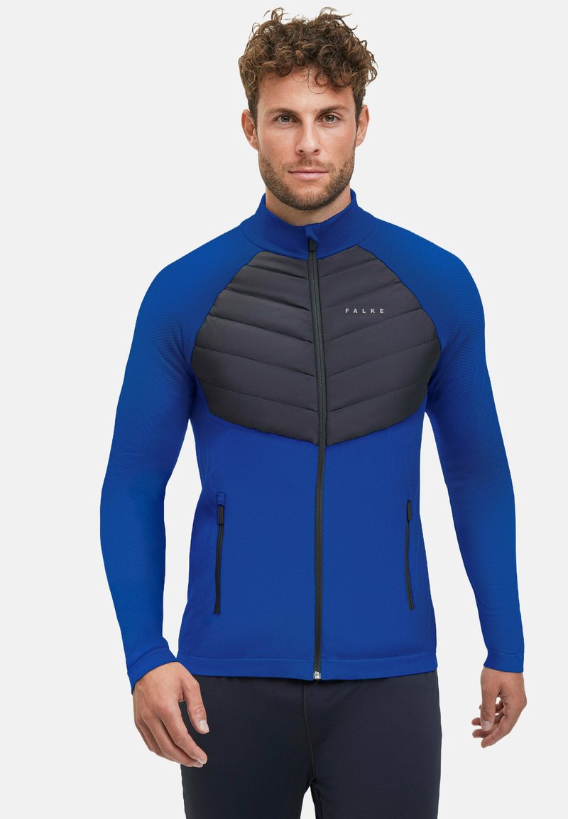Blauwe sportjack met lange mouwen, ritssluiting en een textuur paneel van zwart padding op de borst. Voorzien van dubbele zijzakken en een hoge kraag.
