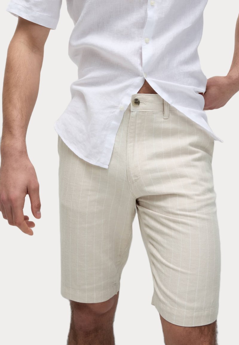 Pantalones cortos beige hasta la rodilla con un patrón de rayas. Confeccionados en una tela ligera, cuentan con un cierre de botón en la parte delantera y bolsillos laterales.