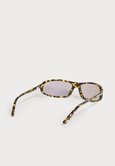 Lunettes de soleil rectangulaires avec verres teintés foncés et montures à motif écaille, reposant sur une surface blanche.