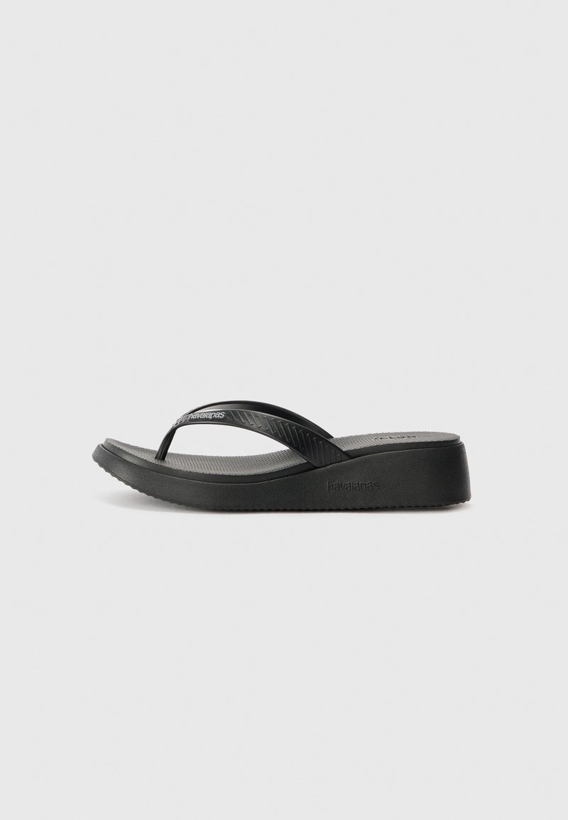 Svart flip-flop med gummistroppar och texturert fotseng. Har en liten plattform og formet design for komfort. Merkenavnet er preget.