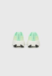 Sports shoes with a light green fabric upper, featuring a textured finish, white midsole, and black rubber accents at the sole. Model number 1080.