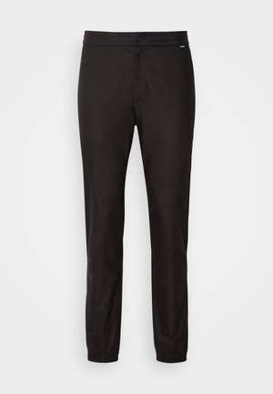 Svarta tights med elastisk midja, avsmalnande bendesign och cuffed avslut. Slät tyg utan synliga mönster eller hårdvara.