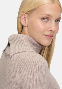 Maglione lavorato a maglia di un delicato rosa chiaro con colletto a coste e dettaglio dei bottoni sulla spalla, caratterizzato da un tessuto testurizzato e una vestibilità aderente.