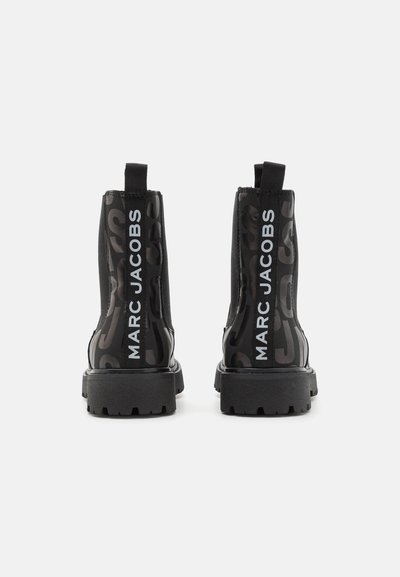 Svarte ankelstøvler med gummisåle, med et teksturert design og store "MARC JACOBS" bokstaver bak. Inkludert elastiske paneler på siden.