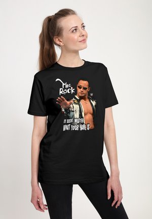 Schwarzes T-Shirt mit einem grafischen Druck einer muskulösen Figur mit Sonnenbrille und dem Text „The Rock“ sowie „Es ist egal, wie dein Name ist.“
