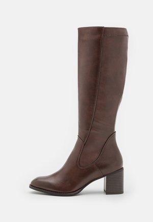 Høj brun læderstøvle med blokhæl, rund tå og sømdetaljer langs siden og fronten.