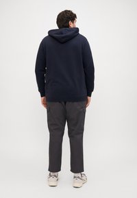 Navy blue hoodie with a kangaroo pocket and adjustable hood, paired with dark gray cargo pants featuring side pockets and a relaxed fit.