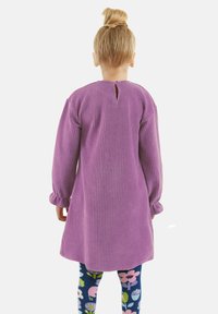 Paarse geribde jurk met lange mouwen en een knoopsluiting aan de achterkant. Draag het over bloemenpatroon leggings met blauwe, roze en groene kleuren.