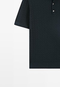 Tmavě zelené polo tričko s krátkými rukávy s texturovaným vzorem copánkového pletení, opatřené tříknoflíkovou légou a kontrastními žebrovanými manžetami a lemem.