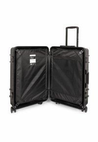 Valigia rigida nera, aperta, con esterno testurizzato, tasca interna in rete e manico retrattile. Include ruote scorrevoli.