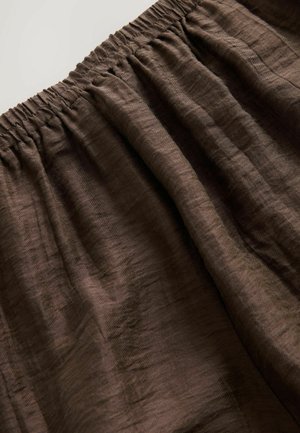 Bruin elastisch materiaal met een licht gekreukt textuur, kenmerkend door zachte plooien en een gathering taille voor een verstelbare pasvorm.