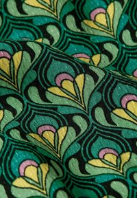 Textil med ett grönt, svart, gult och rosa blommönster; har böjda, bladsformade former och en texturerad yta.