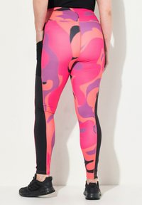 Högmidjade leggings i livlig rosa med lila och svarta abstrakta mönster, med en solid svart sidpanel och en slät textur.