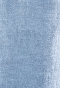 Gros plan d’un tissu tissé bleu clair montrant une texture fine à motif carré.