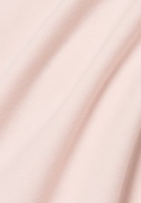 Tessuto di cotone rosa chiaro con una texture liscia e morbida, caratterizzato da delicati ribattini diagonali e pieghe morbide.