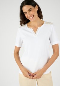Witte katoenen T-shirt met korte mouwen en een v-hals, versierd met textuuraccenten op de schouders. Glad materiaal, casual pasvorm.