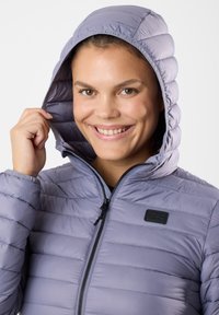 Light purple insulated jacket with a hood, zip closure, and horizontal quilted pattern. Features a black logo patch and smooth texture.