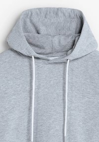 Sudadera gris con capucha y textura suave, con cordón ajustable y un pequeño logo bordado en el pecho.
