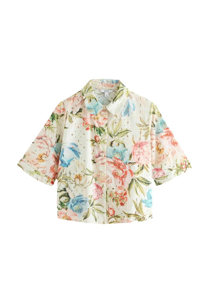 Blommig kortärmad blus med vit bakgrund, pastellrosa och blå blommor, samt ett strukturerat tyg med små perforeringar.