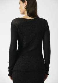 Maglione nero a maglia con pannelli in tessuto testurizzato e peloso, maniche lunghe, progettato con una silhouette aderente e accenti a costine.