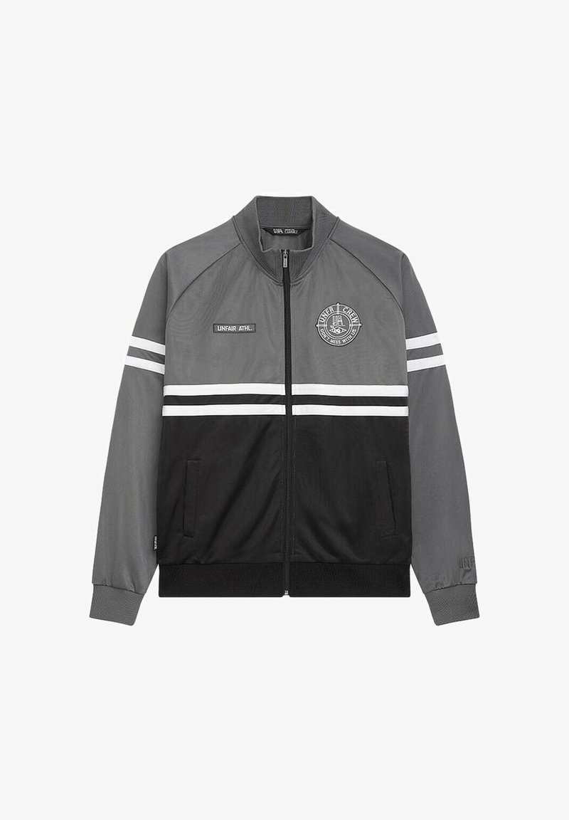 Giacca track grigia e nera, con zip frontale, due tasche, strisce bianche sulle maniche e un logo circolare sul petto.