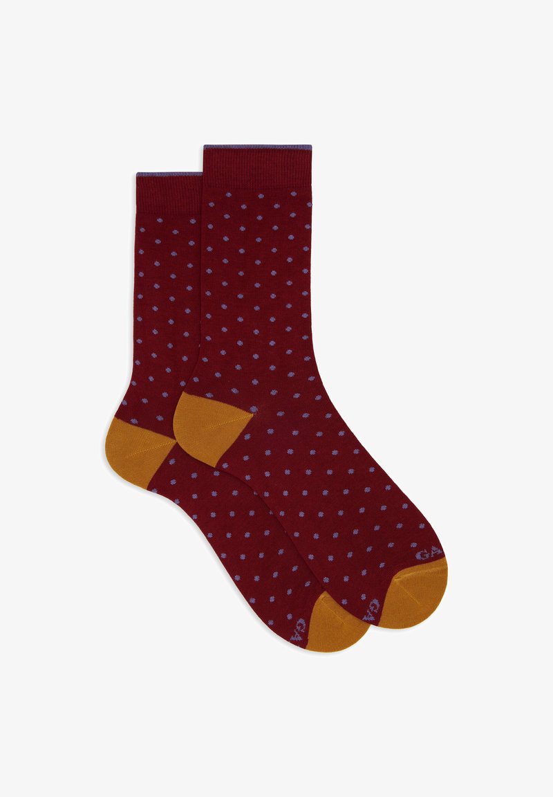Ein Paar weinrote Socken mit kleinen hellblauen Punkten und kontrastierenden senfgelben Fersen und Zehen auf weißem Hintergrund.