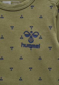 Olivgrön bomullsskjorta med ett blått bi-mönster och en framträdande blå "hummel"-logotyp. Crew neck-design med korta ärmar.