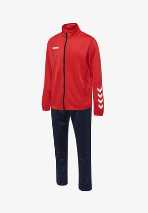 Röd sportträningsdräkt som består av en zip-up jacka med vitt logotyp och chevrondesign, kombinerad med marinblå byxor i ett mjukt, lätt material.