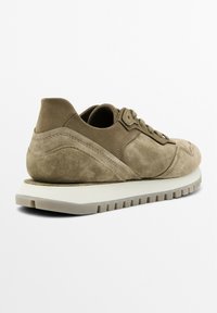 Khaki suede sneaker with a rounded toe and angled side panels. Thick white rubber sole with pronounced treads. Lace-up design and sturdy stitching.