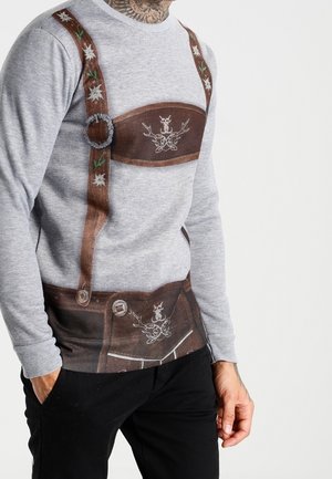 Grå sweatshirt med trykt design af brune lederhosen med blomsterdetaljer og dekorativ spænde. Struktureret stof simulerer traditionelt tøj.