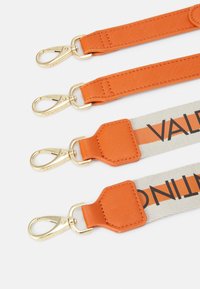 Vier Riemen mit orangefarbenem Stoff, goldenen Hardware und unterschiedlichen Designs: zwei einfarbig orange, ein Canvas mit dunkler Schrift und ein gemusterter Akzent.