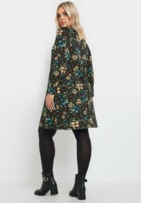 Mustakukkainen mekko pitkähihaisilla, jossa on värikkäitä kukkia sinisen, keltaisen ja punaisen sävyissä. Yhdistetty mustiin sukkahousuihin ja nilkkureihin.