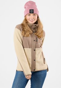 Giacca in pile beige e marrone, con collo alto, chiusura a pressione e tasche laterali. Accompagnata da un berretto rosa.