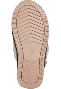 Vaalean värinen kumipohja syvillä urilla, joka on suunniteltu pitämään hyvin; ympäröivä tekoturkis päällinen beige- ja tummansinisin yksityiskohdin, joka näyttää pyöreältä.