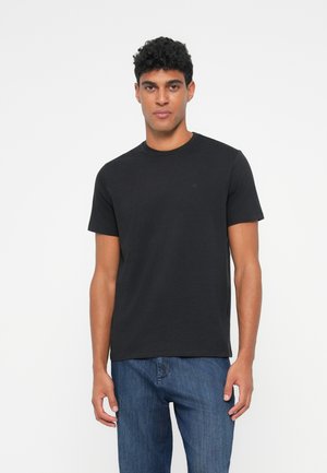 Schwarzes T-Shirt mit kurzen Ärmeln aus Baumwolle, runder Ausschnitt und kleinem Logo auf der Brust, kombiniert mit blauen Jeans aus Denim.