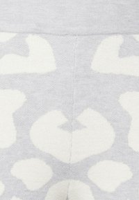 Tecido de malha cinza com um padrão de estampa de leopardo em forma de coração branco. Textura suave com um detalhe de costura no centro.