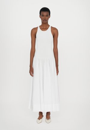 Witte tankjurk met geribbelde textuur, aansluitend lijfje en een losse, geplooide rok. Draag met lichtgekleurde, puntige instappers. Eenvoudig ontwerp.