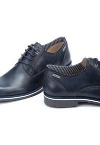 Navy blue leather shoes with a smooth finish, lace-up design, striped interior, and a contrasting white sole detail.