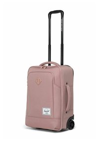 Valise à roulettes souple rose avec une poignée extensible noire, deux roues, poche zippée à l'avant et poignée latérale pour un transport facile.