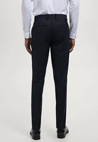 Navy dress trousers with a tailored fit. Features two back pockets, belt loops, and smooth fabric texture. Fitted at the ankles.