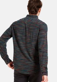 Flerfärgad randig skjorta gjord av texturerat tyg. Har en krage, lång ärm och en rak skärning med subtil sömdetaljering.