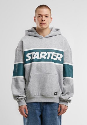 Grijze hoodie met een groot "STARTER" logo in teal, met witte strepen op de mouwen en een voorzak. Zacht materiaal, relaxte pasvorm.