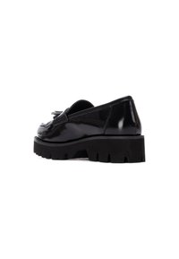 Mocasines de charol negro con suela de goma gruesa, que presentan un detalle decorativo de flecos en la parte delantera y un acabado suave y brillante.