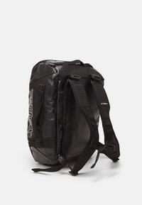Sac à dos étanche noir avec des bretelles réglables, fermeture par enroulement et logo "TERREX" bien visible sur le côté. Surface texturée avec des accents en matériel.